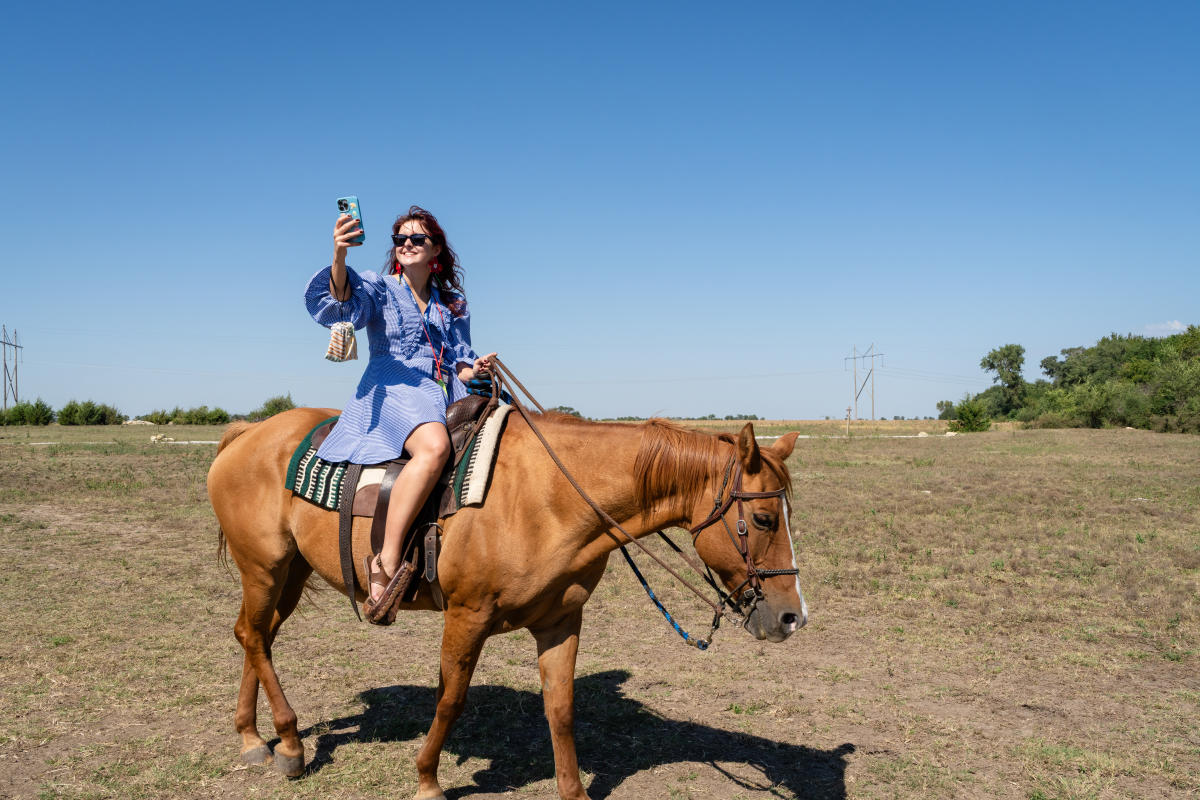 A woman smiles as she takes a selfie while riding a horse at Diamond Springs Ranch.