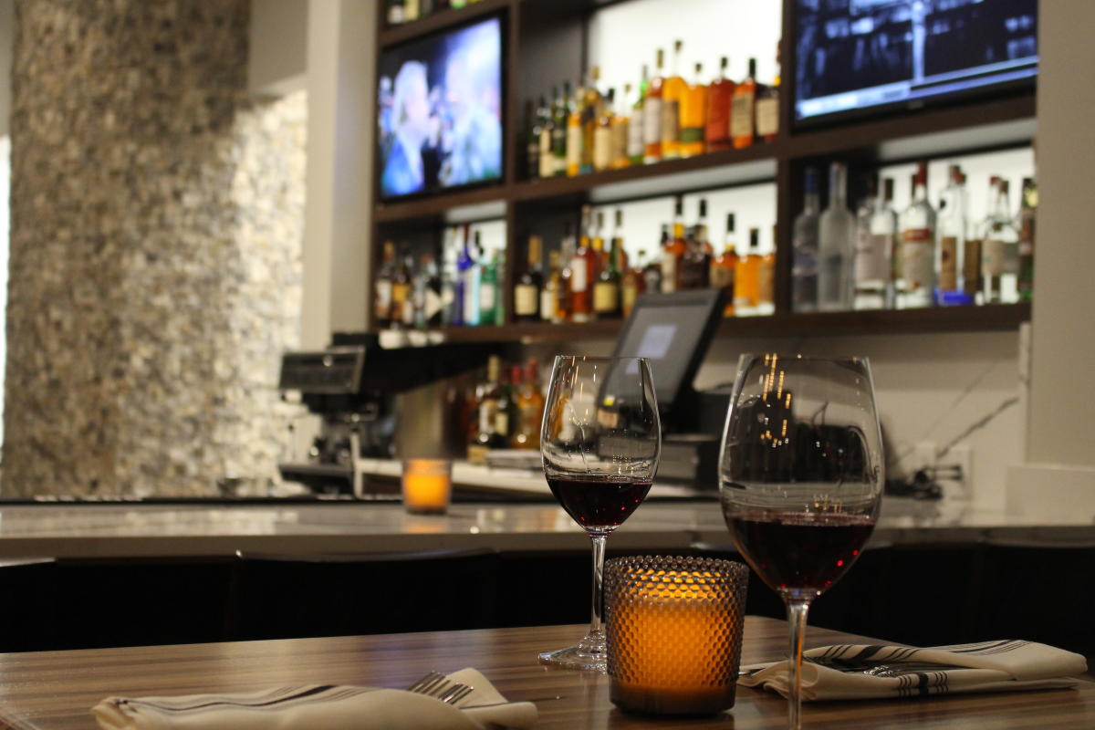 Two wine glasses sit on a table with the bar at Wine Dive in the background