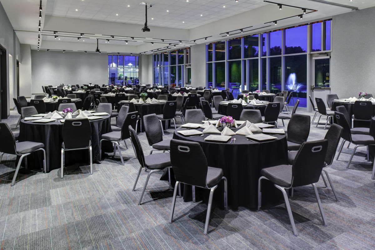 Chairs are positioned around round tables inside a meeting room at Aloft hotel in northeast Wichita