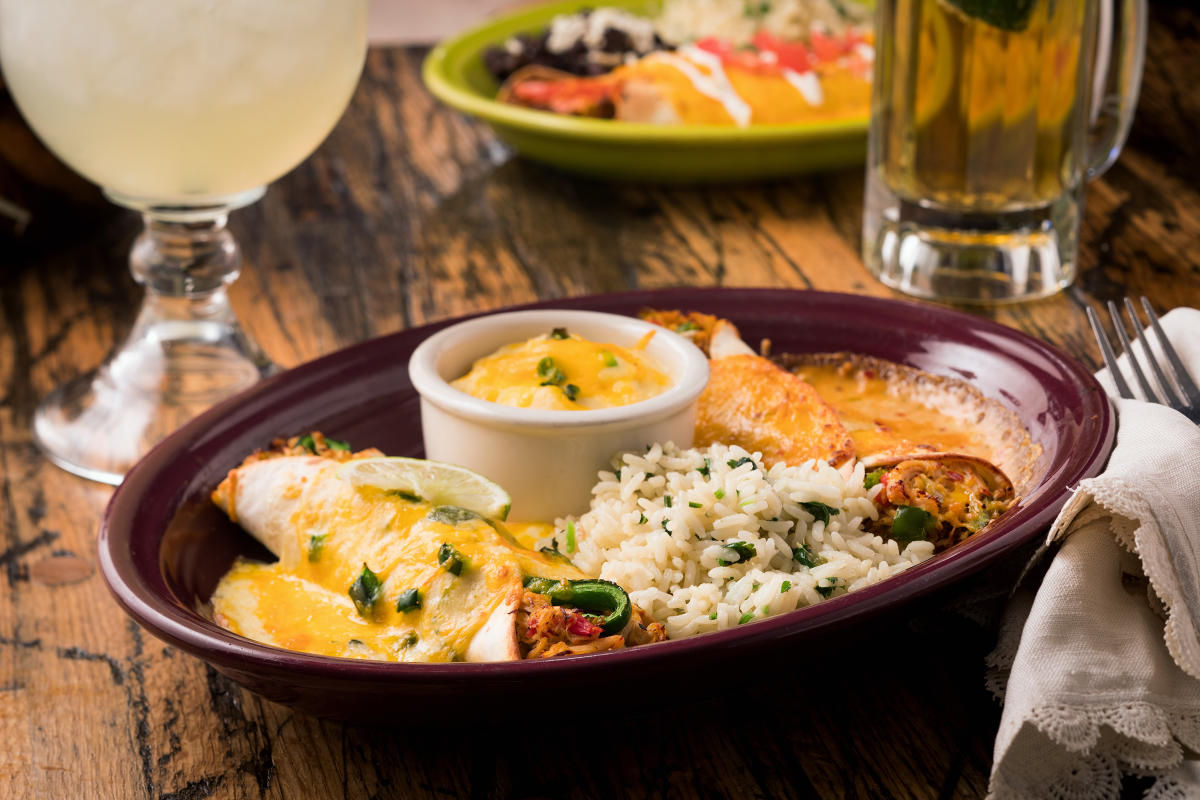 A plate of enchiladas and rice is served with a beer and margarita at Carlos O'Kelly