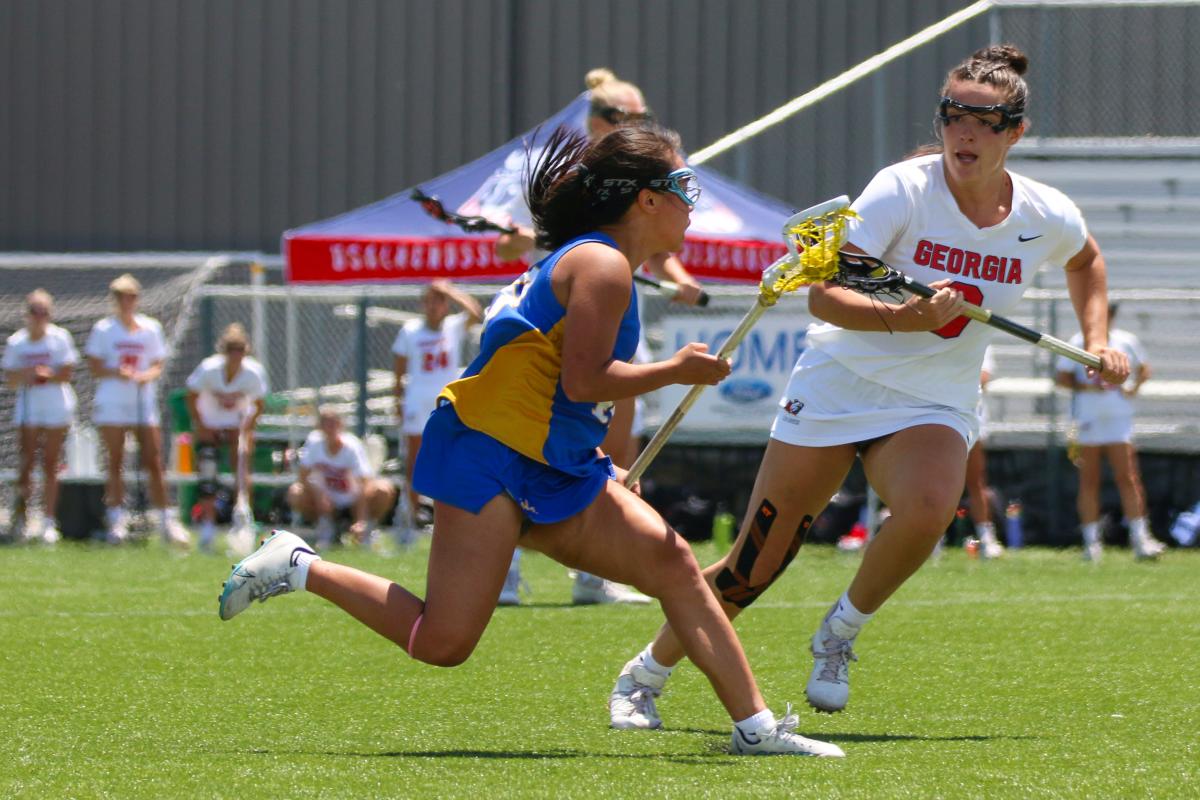 Two women compete in a Lacrosse match at SCHEELS Stryker Sports Complex