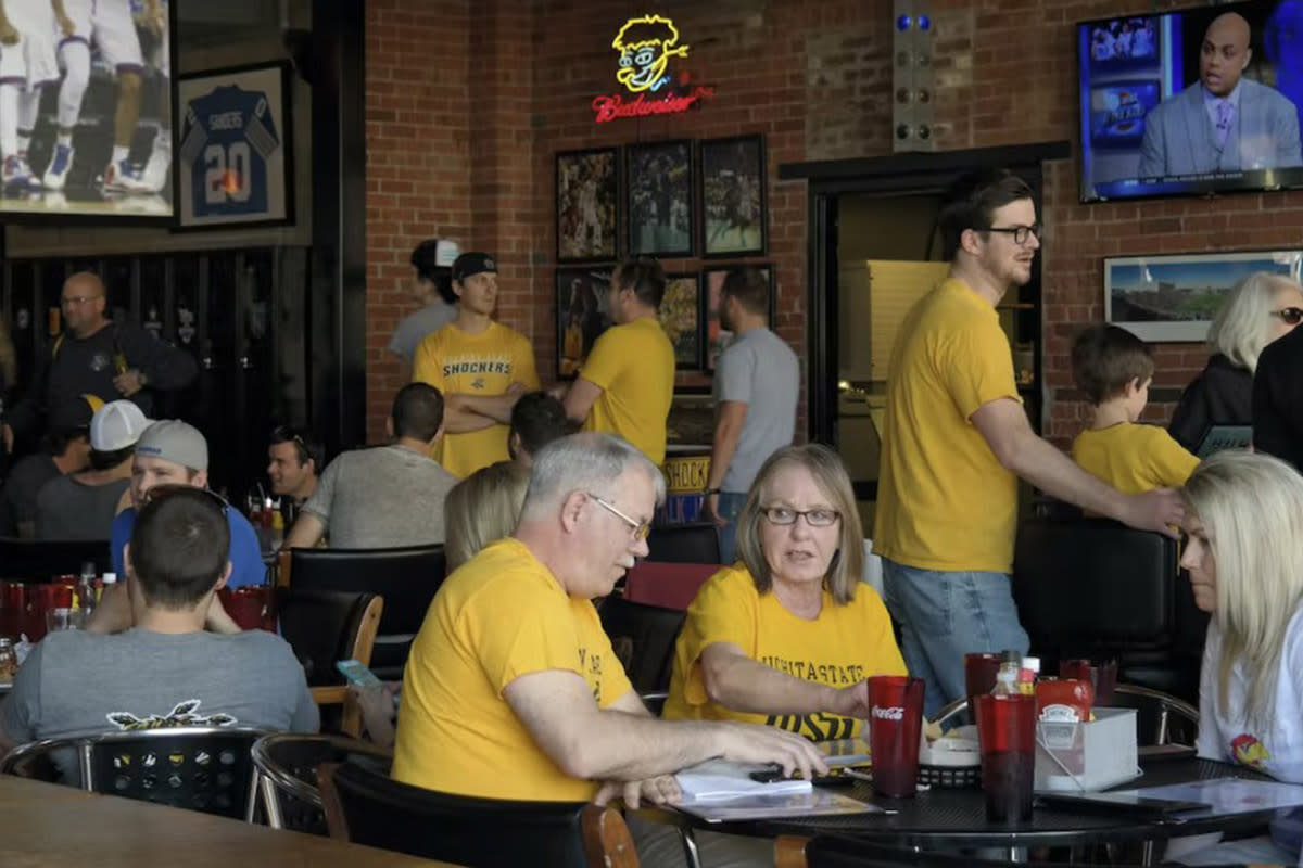 Three patrons wear their WSU shirts while watching a game and eating at Pumphouse