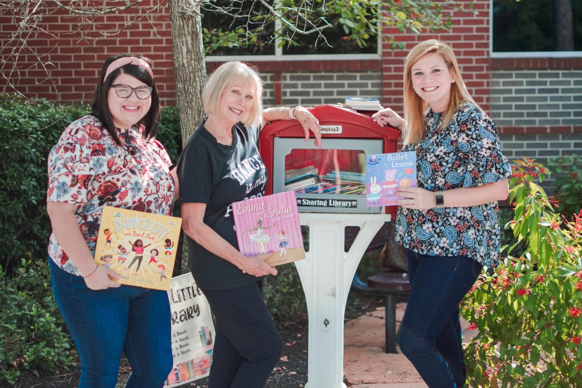 The Cynthia Woods Mitchell Pavilion Team standing next to Little Free Library where they're donating books for Cynthia Woods Mitchell's 101st Birthday