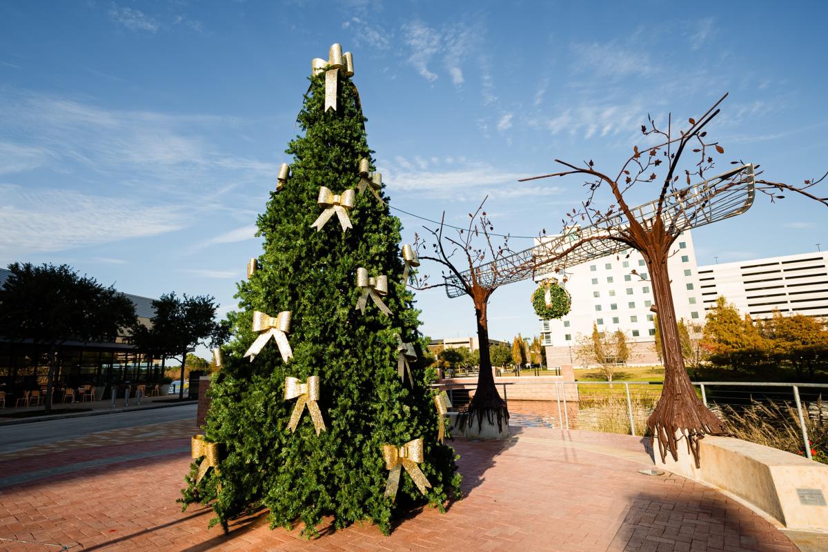 The Christmas Tree at Hughes Landing sits on the corner between Escalante's and the "Dream.It.Do.It" public art piece. The tree is decked with sparkly gold ribbons.