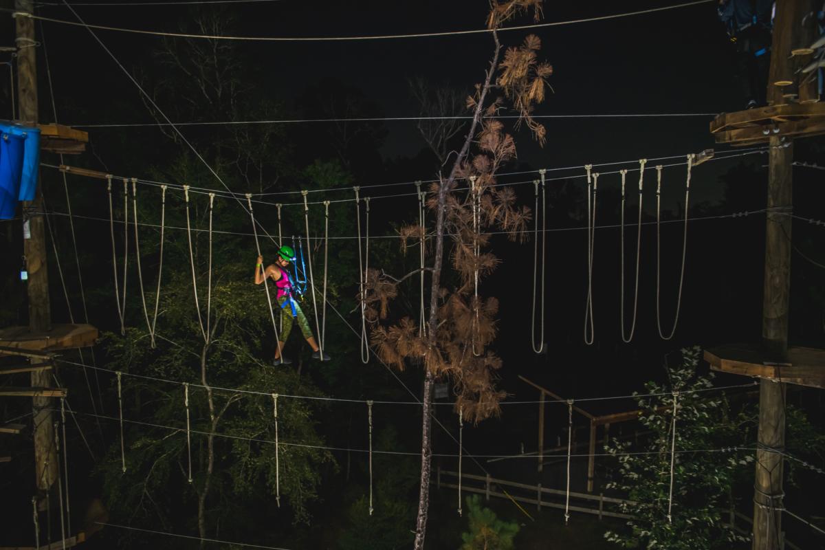 woman climbing at Texas TreeVentures course at night