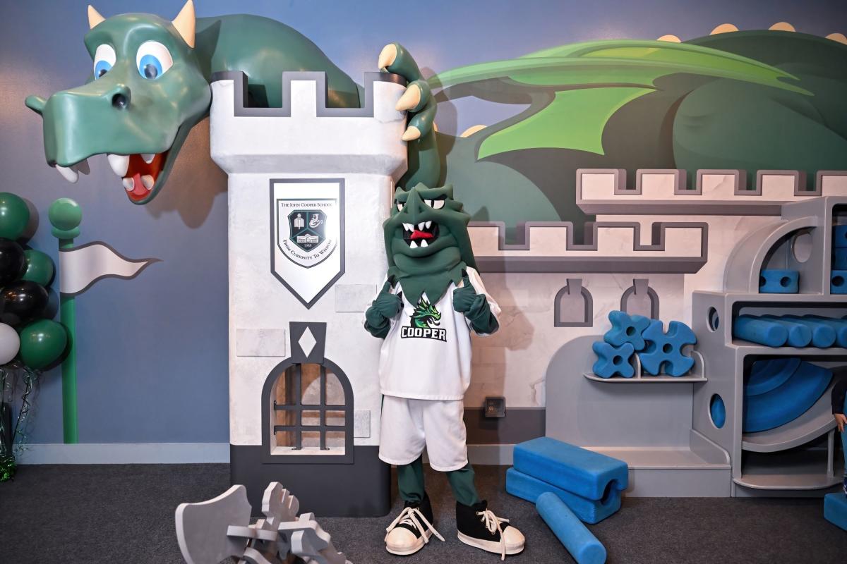 John Cooper Mascot standing in front of the John Cooper School Dream and Build Exhibit at The Woodlands Children's Museum