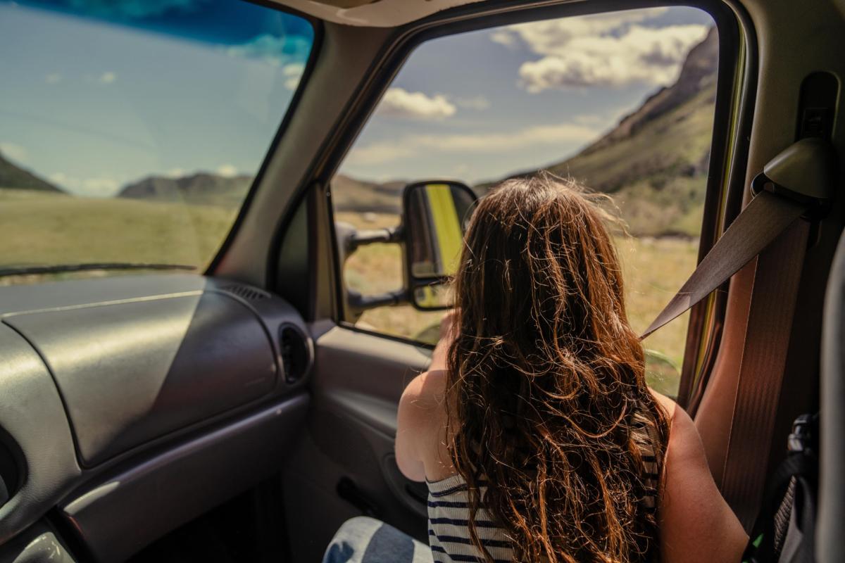 Little girl looking out a car window at mountains.