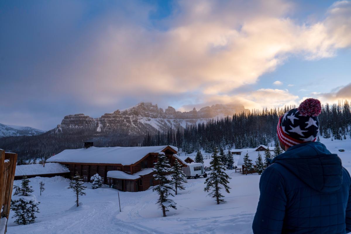 Man overlooking Brooks Lake Lodge in winter with mountain range in the background