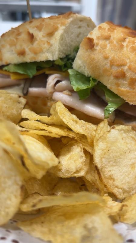 Sandwich in the background and potato chips in the foreground.