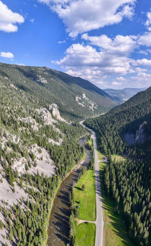 A scenic photo of Montana Highway 191 traveling in a valley between mountains alongside a river.