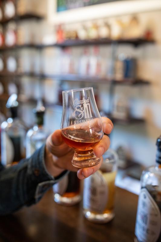 A close up of a man holding a sample of a spirit at Cardinal Sin in St. Charles, Missouri.