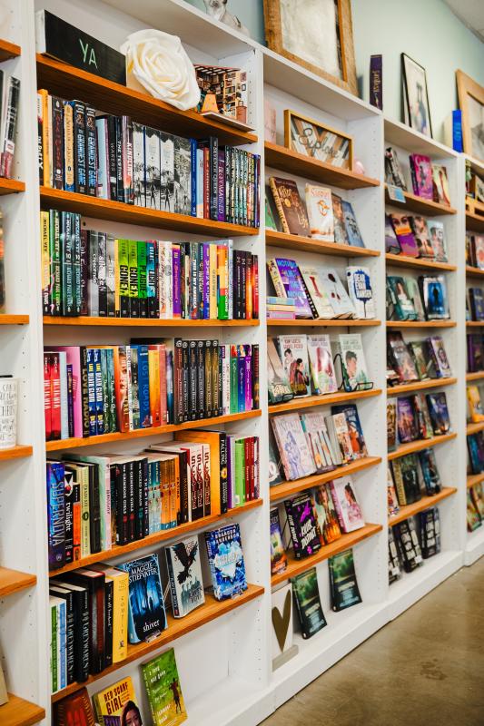 A wall of neatly displayed young adult fiction books and colorful book-themed knickknacks.