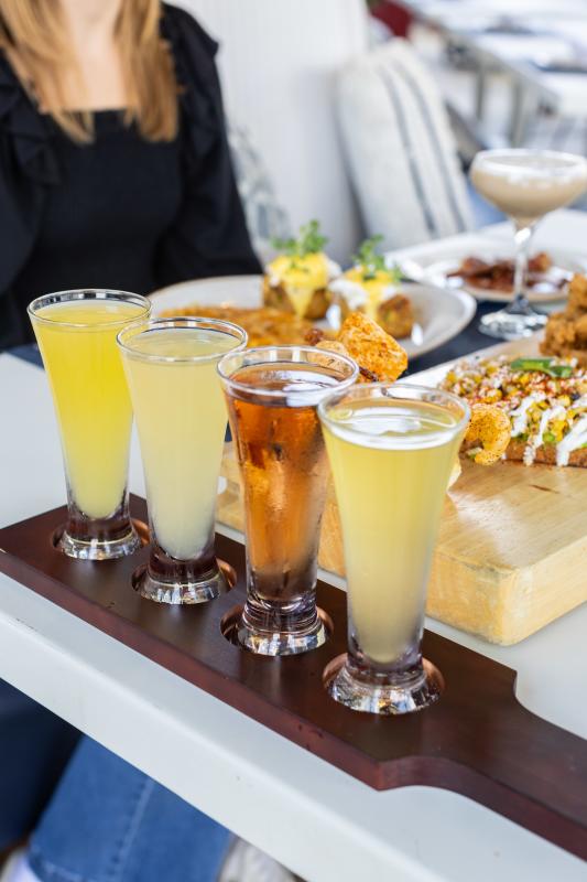 Four mimosas on a tray sit on the edge of a State Fare patio table, which is set for a big outdoor lunch.
