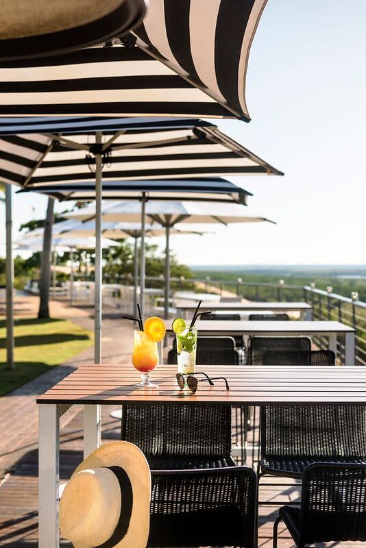 Two cocktails sit on an alfresco table at the Mangrove Hotel alongside a sun hat and sunglasses
