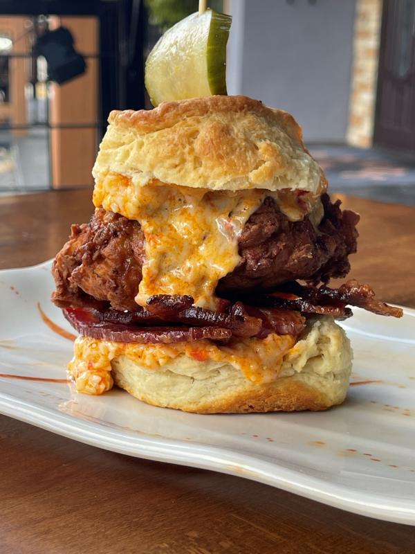 A biscuit is stacked high with chicken, bacon, and pimiento cheese.