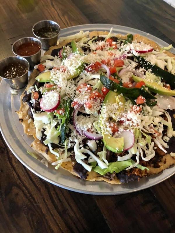 fried corn tortilla piled with toppings and served with salsas at Taqueria Los Hermanos