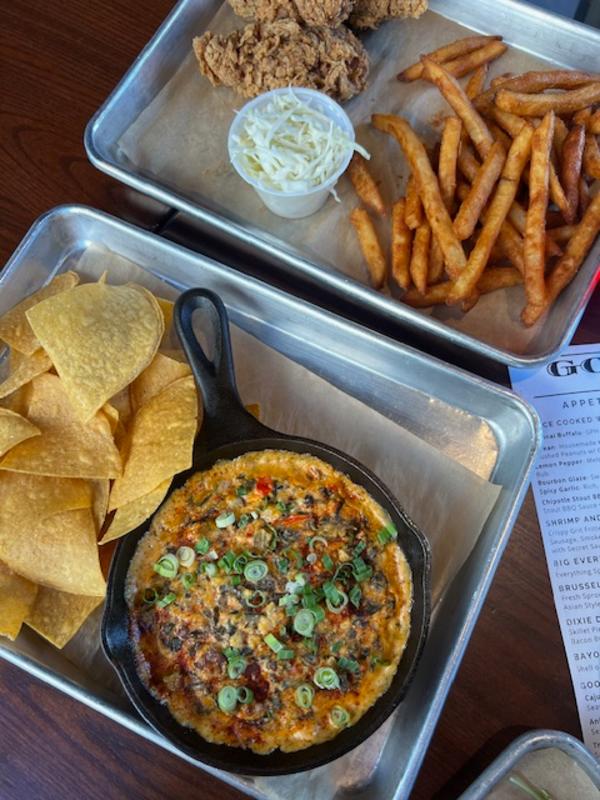 Two metal trays with pizza, chips, and fries on a table