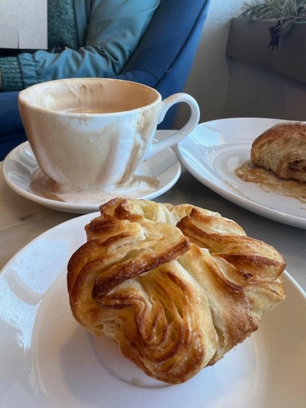 Pastry on a white plate and white tea cup on a table