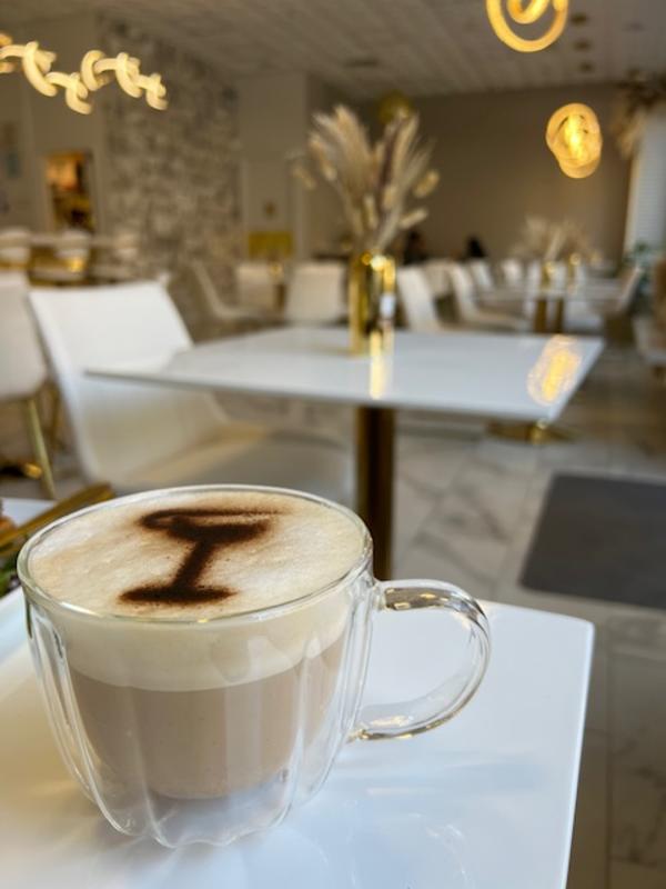 Clear mug of coffee on a table with tables in the background