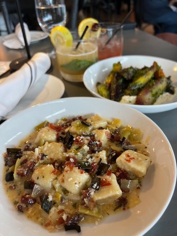 Two plates of Italian food on a table with drinks