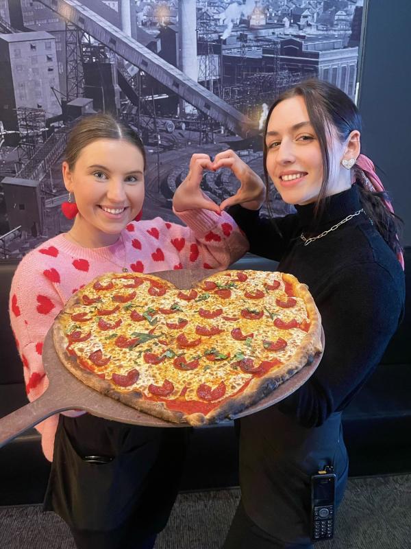 two women holding a heart-shaped pizza from Colarusso's Coal Fired