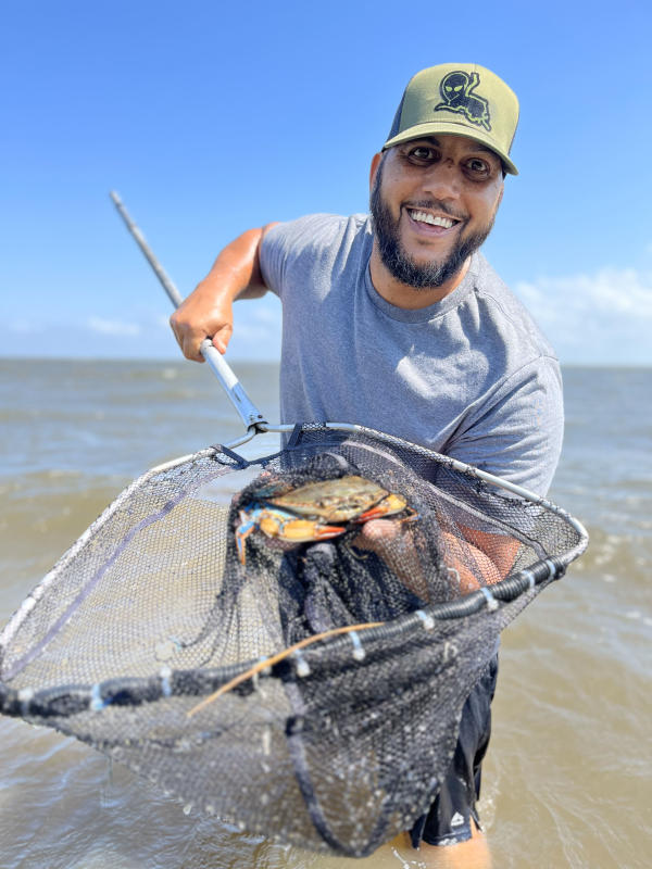 Corey LaBostrie holds a Louisiana Blue Crab in his dip net