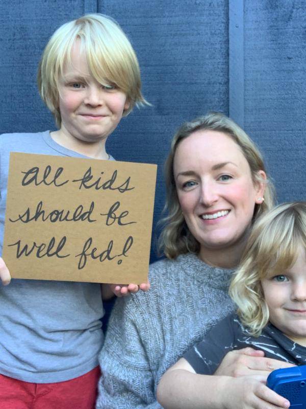 Fanny Adams of Trout Lily Ranch and children hold sign saying "all kids should be well fed"