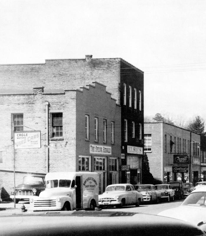 The Sylva Herald office and Elsie’s dress shop on Main Street in Sylva, NC, in 1956, with a Nantahala Creamery truck and Rexall Drugs sign nearby