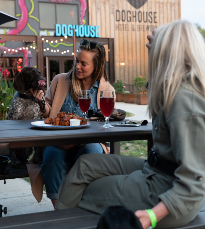 Two women and their dogs sitting on patio table outside Brewdog Doghouse