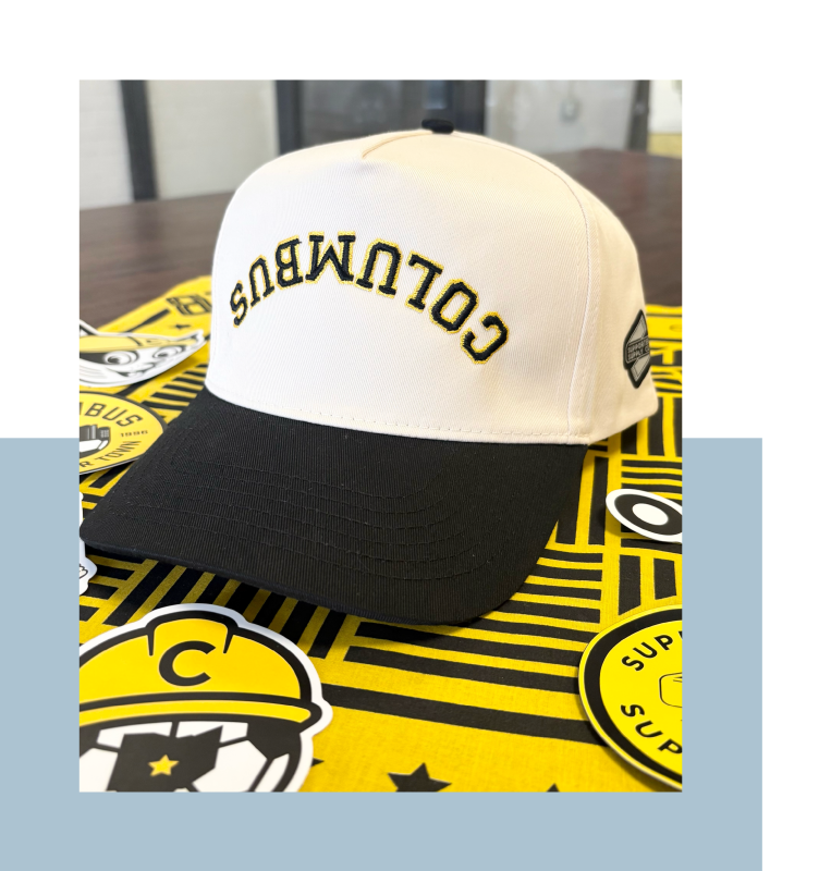White hat with black brim and the word "Columbus" upside down in black and yellow