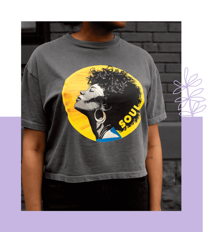 Woman wearing a gray cropped T-shirt with a circular graphic of a woman’s profile against a yellow background with the word “SOUL"