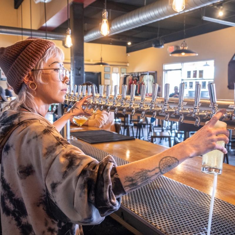A worker fills two glasses of beer at Canteen Brewhouse