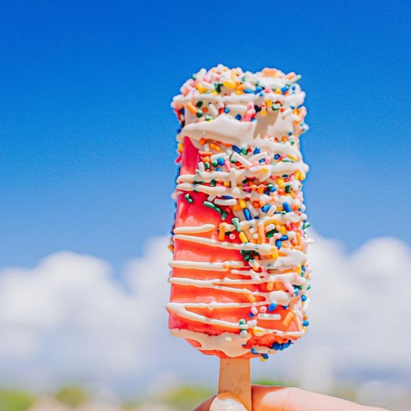 A paleta from The Paleta Bar is held up against the Albuquerque sky.
