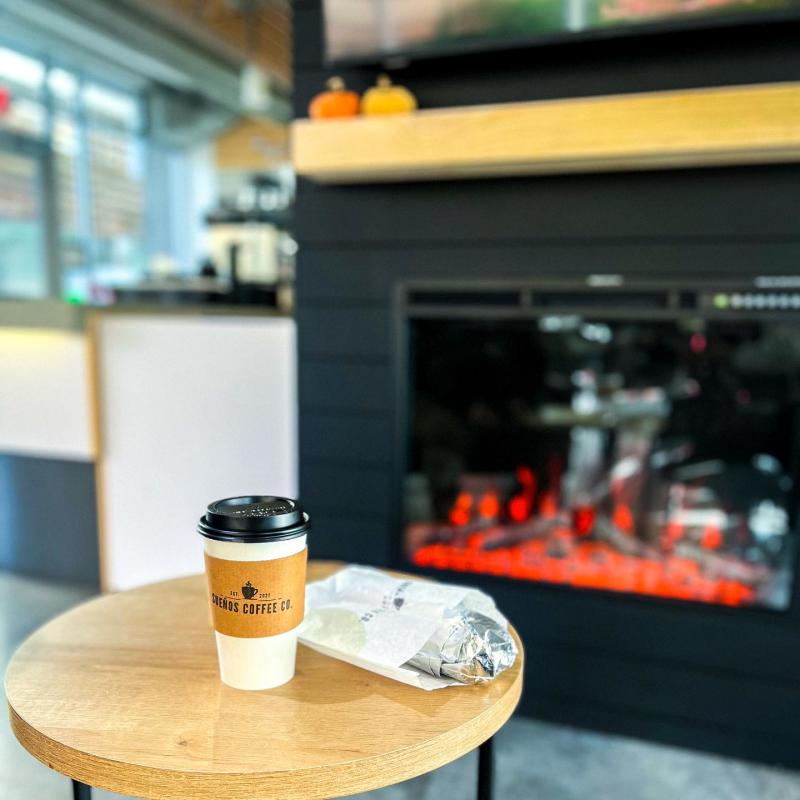 A coffee and breakfast burrito from Sueños Coffee sit on a table inside the coffeeshop.