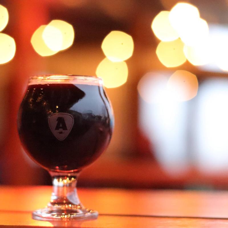 A dark beer in a flared glass sits on a table.