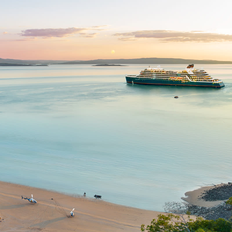 View of APT Kimberley Cruising - Seabourn ship moored alongside a beach on the  Kimberley coast with helicopters on the beach.