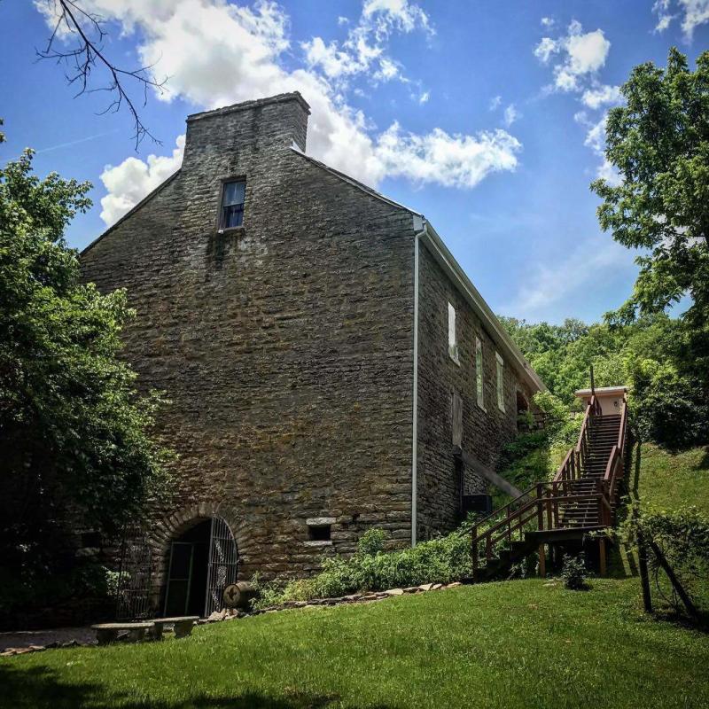 Stone building under a blue sky surrounded by green grass at Baker Bird Winery