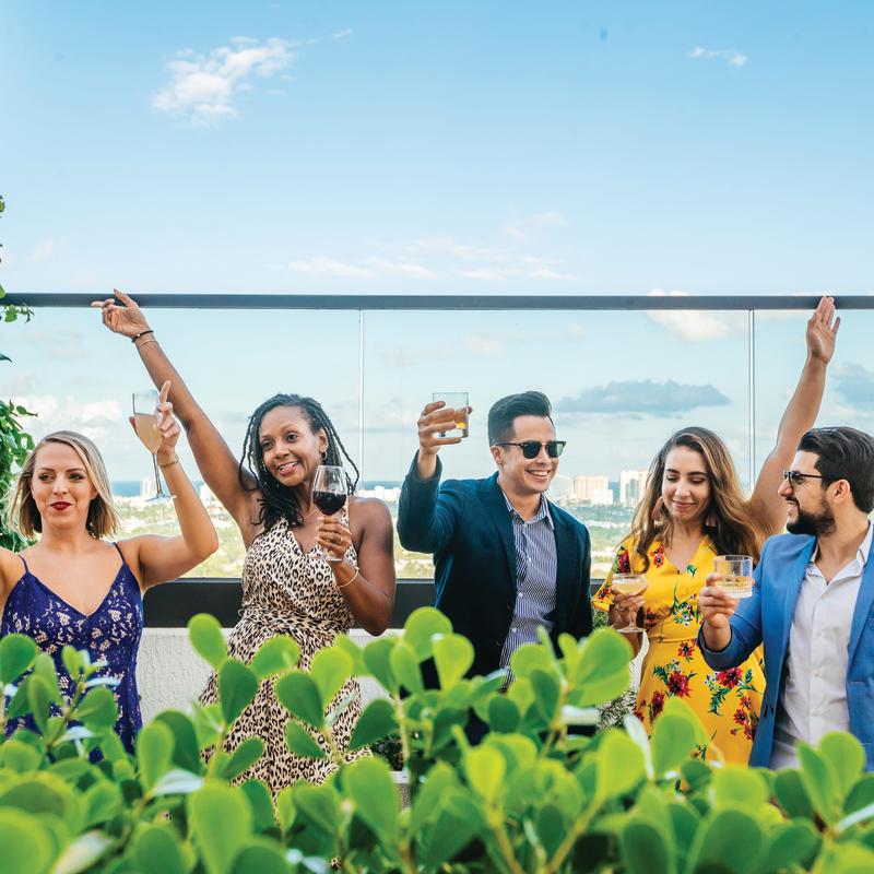 Friends raising glasses to toast from a rooftop bar in Fort Lauderdale