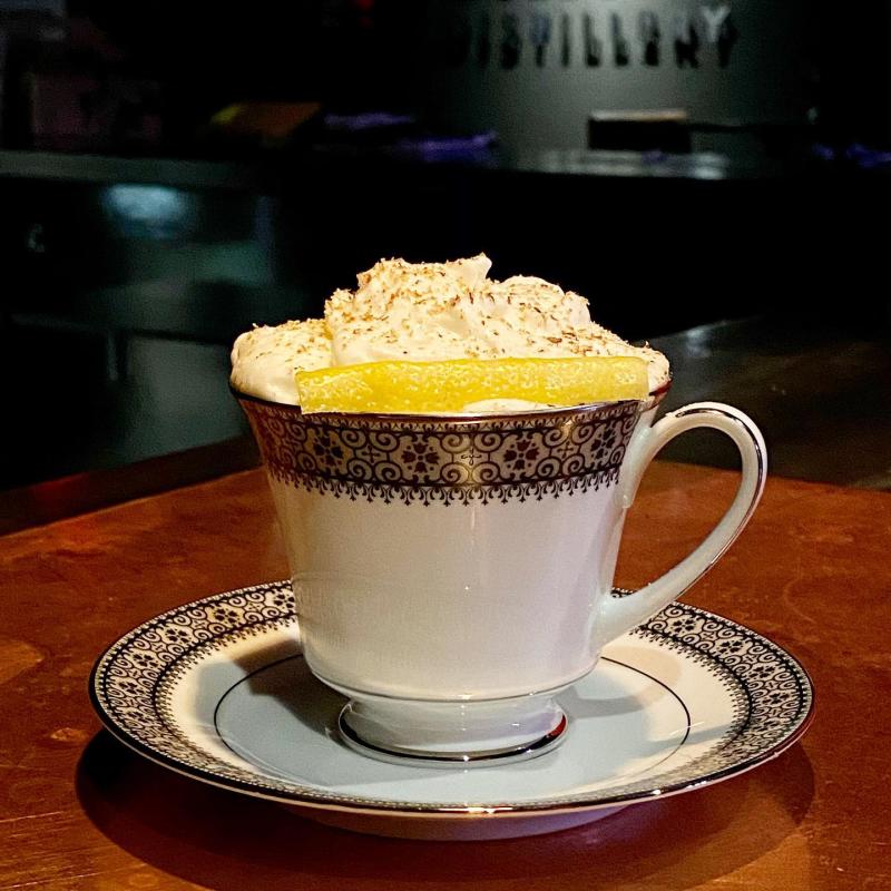 Hot Toddy drink in a fancy teacup with whipped cream on top