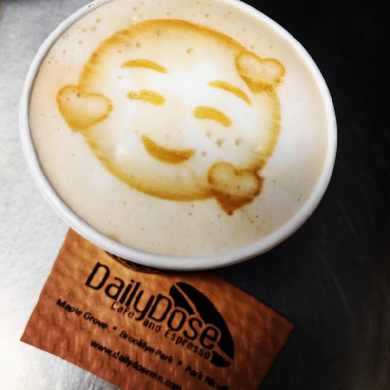 A cup of coffee with a smiley face in the foam from Daily Dose