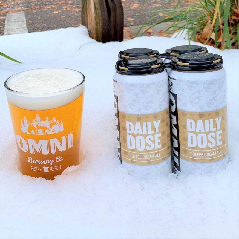 Two cans of beer with the words "Daily Dose" on the label next to a full glass of beer with the words OMNI Brewing Co.
