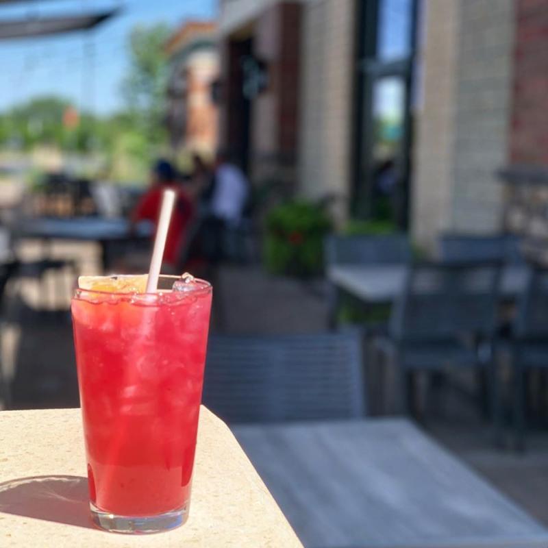 A red mixed drink sits on a patio table at Rock Elm at the Grove