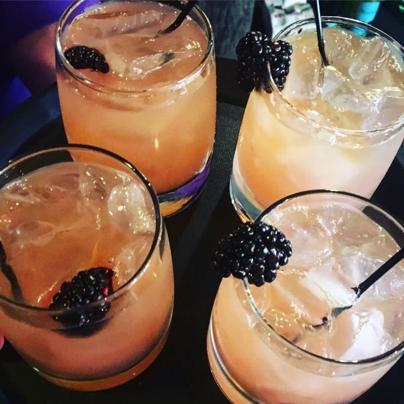 four bourbon glasses holding fruity bourbon cocktails and blackberries at the purple poulet bourbon bistro