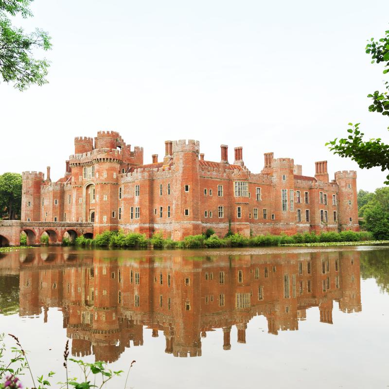 Herstmonceux Castle - a red brick building with towers reflected in the lake