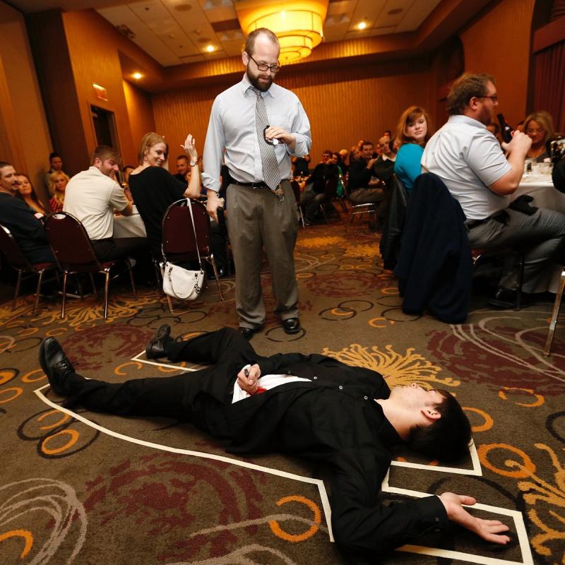 man lying on ground with tape around him for dinner detective promo
