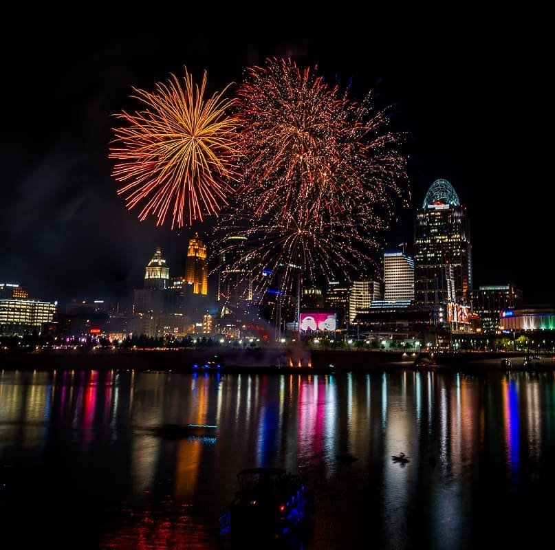 Several orange bursts of fireworks over Cincinnati seen from the Northern Kentucky riverbank on the Ohio