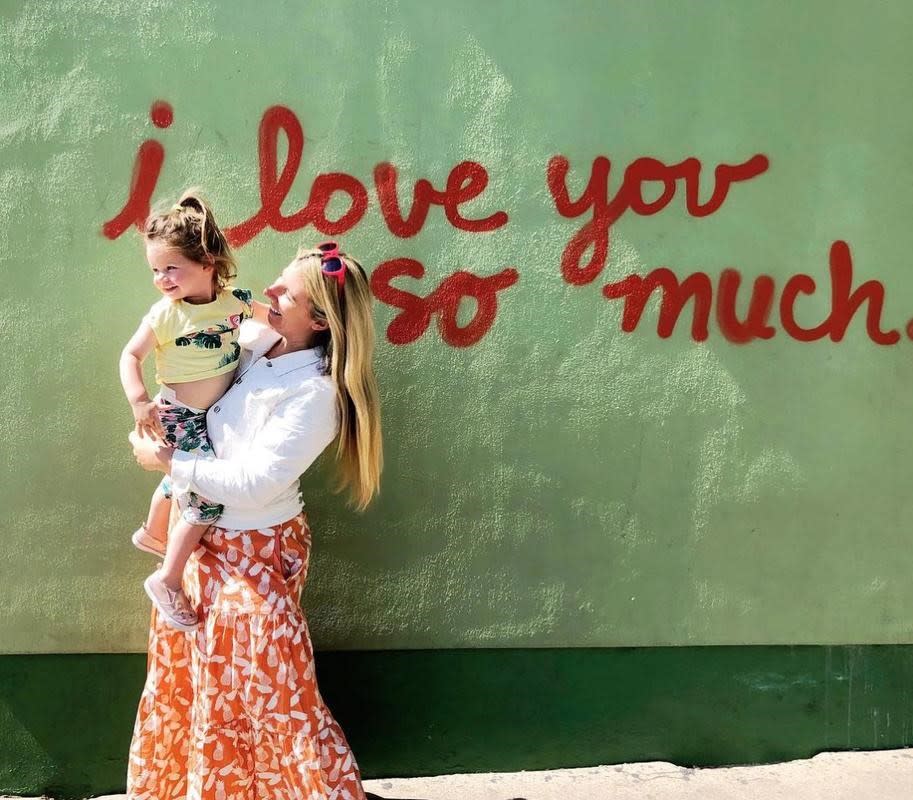 woman holding daughter in front of i love you so much mural at jos in austin texas
