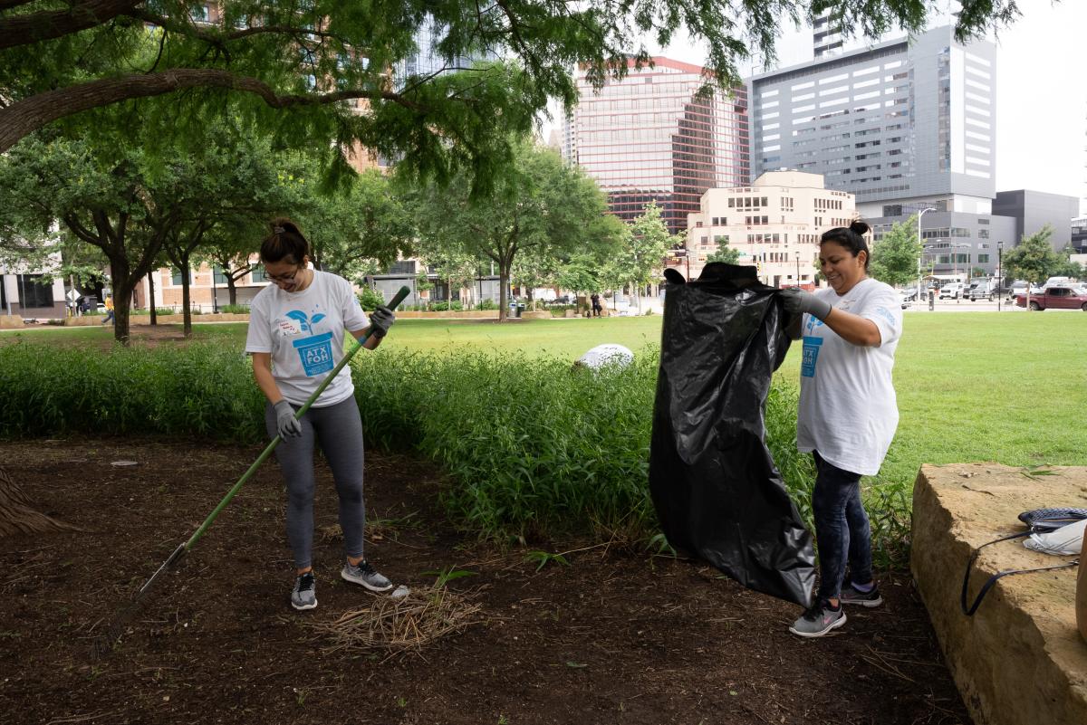 Image of two people raking and pickin up trash in the park.