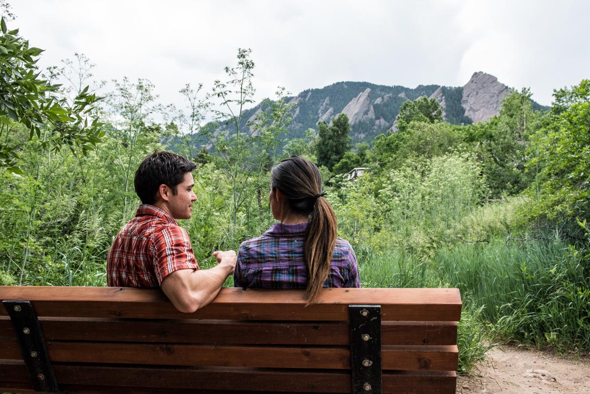 Couple sitting on a bench overlooking the Flatirons