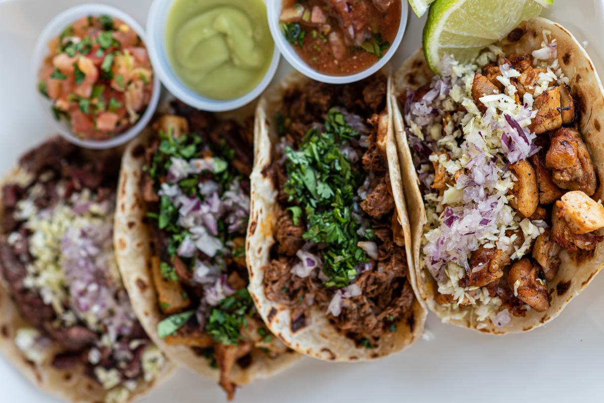 a plate with four street-style tacos with grille meats